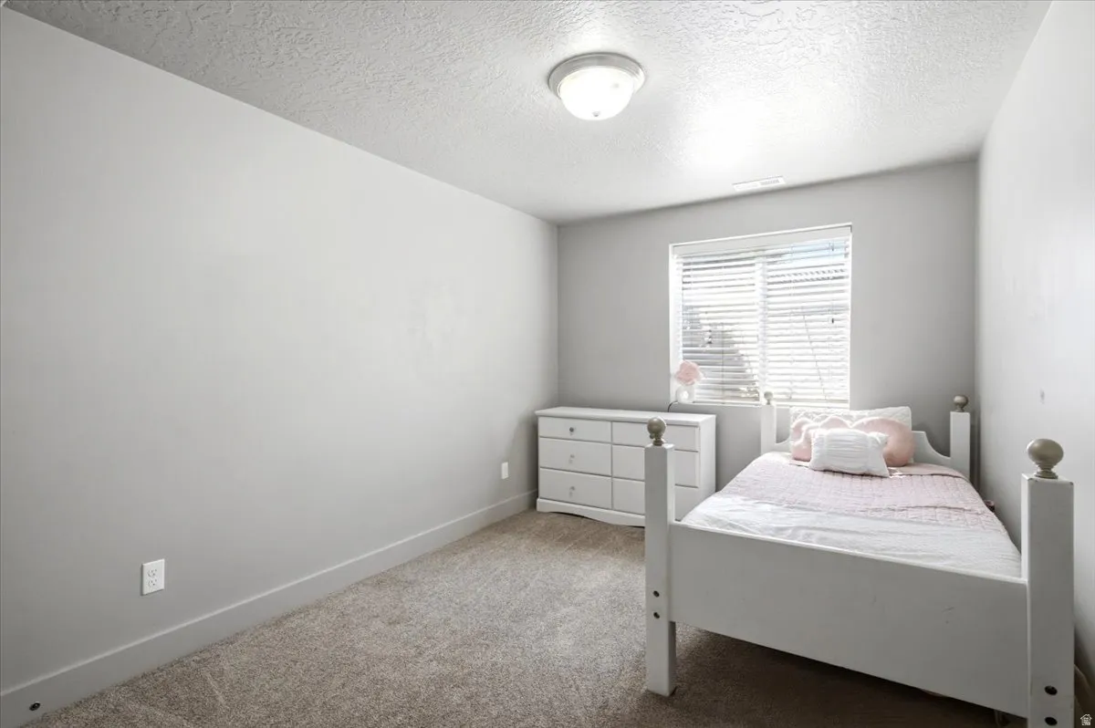 Neutral-toned room featuring a single window with horizontal blinds, providing natural light