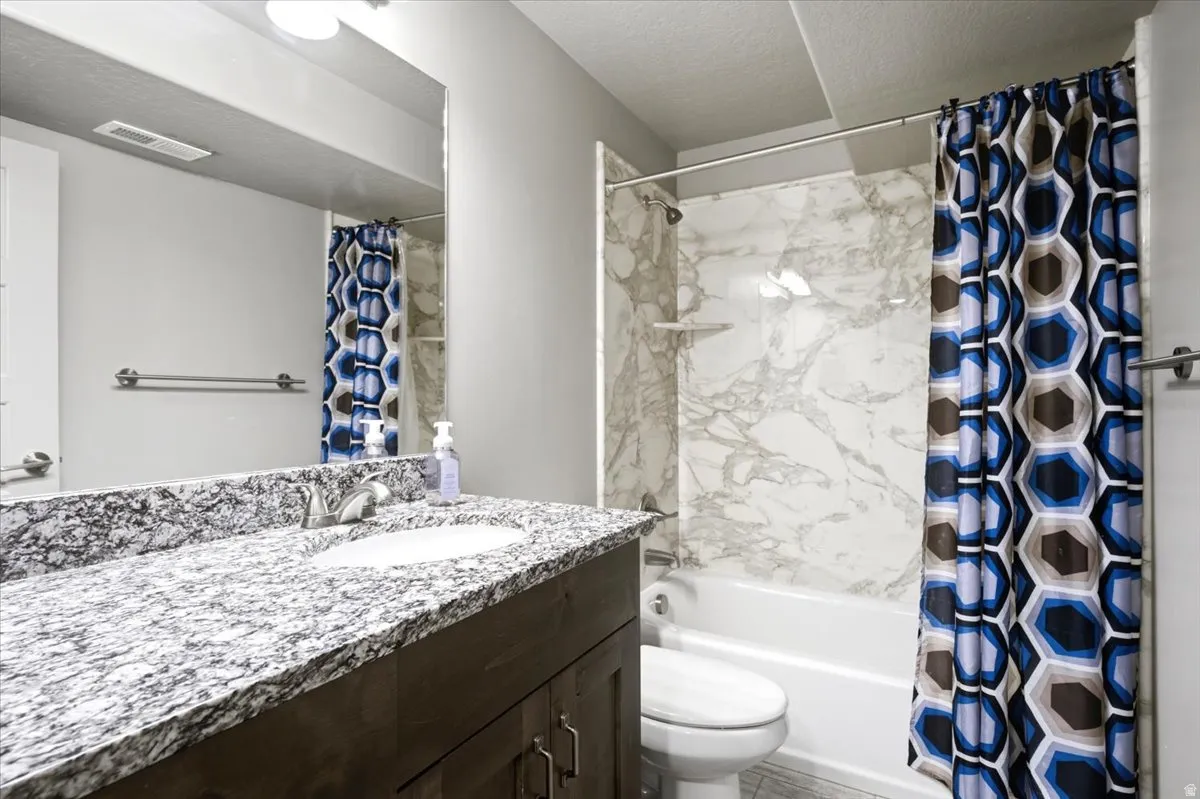 Bathroom vanity with a granite countertop, integrated sink, and dark wood cabinetry