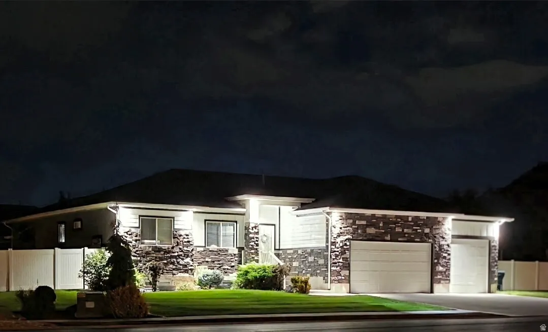 Exterior stone accents, dual garage bays, privacy fencing, manicured lawn, and multiple architectural windows
