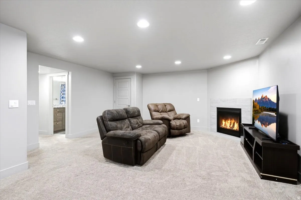 Carpeted interior space featuring a corner fireplace with a tiled surround