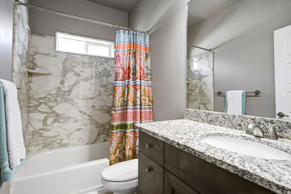 Bathroom featuring a white tub with marble-patterned surround, an integrated shelf, and an overhead window