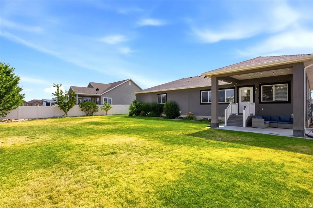 Expansive lawn area with a covered patio featuring a concrete surface, recessed lighting, and direct access to the interior