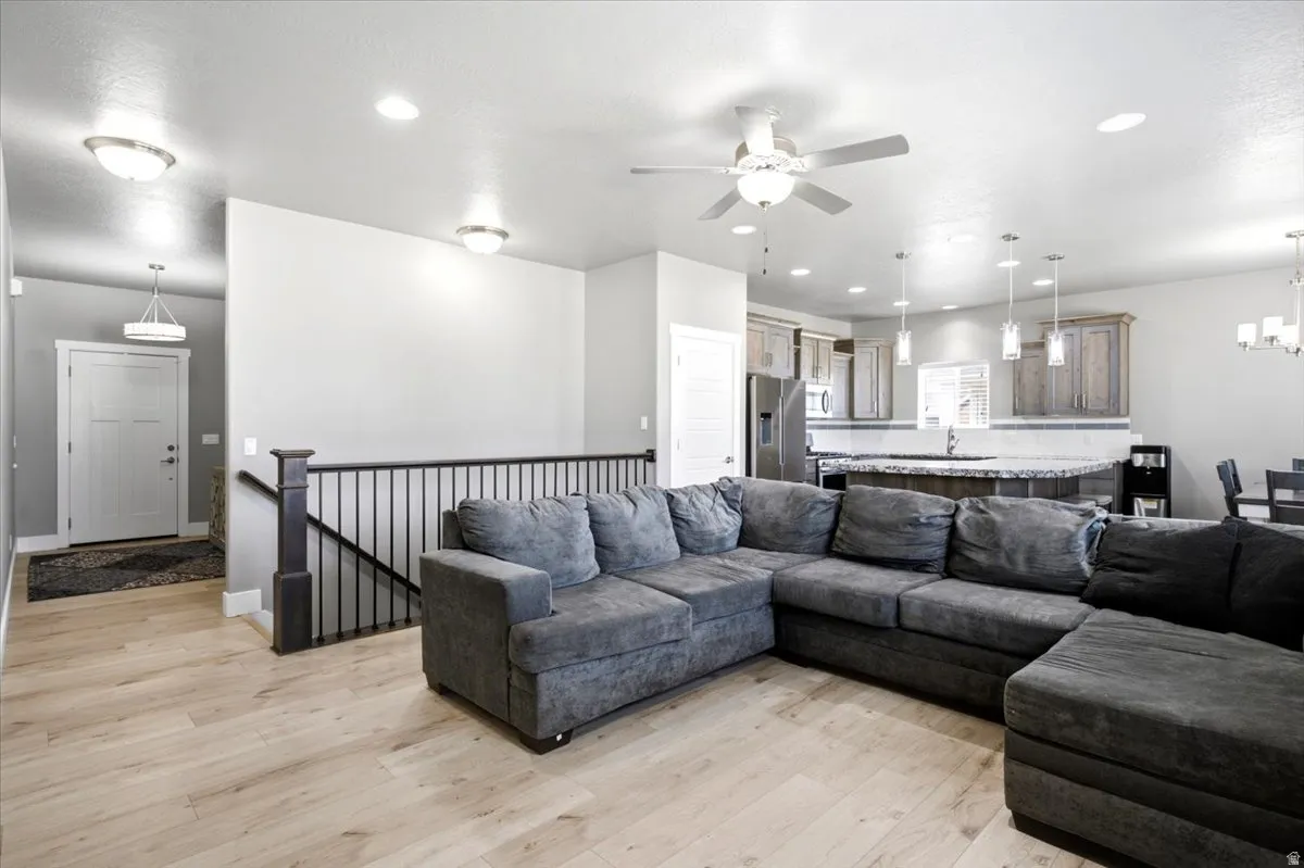 Open-concept living area featuring light wood-finish flooring, recessed lighting, and a contemporary ceiling fan