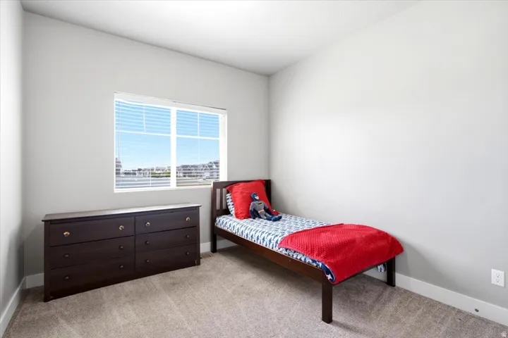 Bright room featuring a large window, neutral wall paint, and light-toned carpet flooring