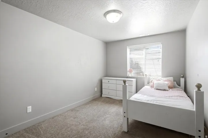 Neutral-toned room featuring a single window with horizontal blinds, providing natural light