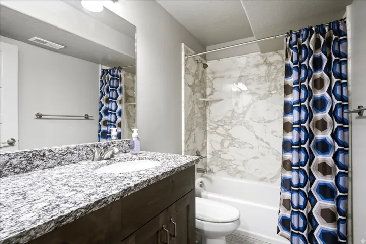 Bathroom vanity with a granite countertop, integrated sink, and dark wood cabinetry