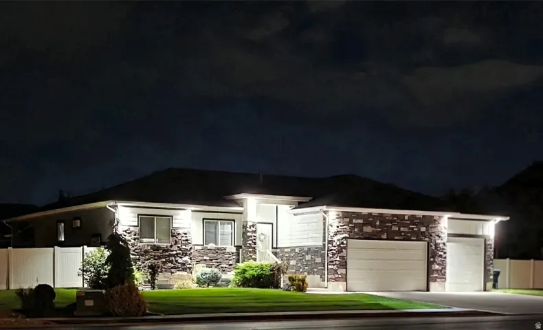Exterior stone accents, dual garage bays, privacy fencing, manicured lawn, and multiple architectural windows
