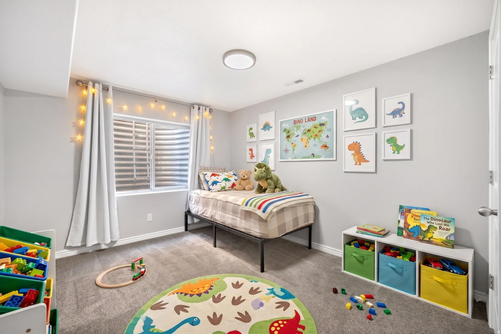 Spacious room featuring light gray walls, plush gray carpet, a window with horizontal blinds, a white door, and a flush-mount ceiling light