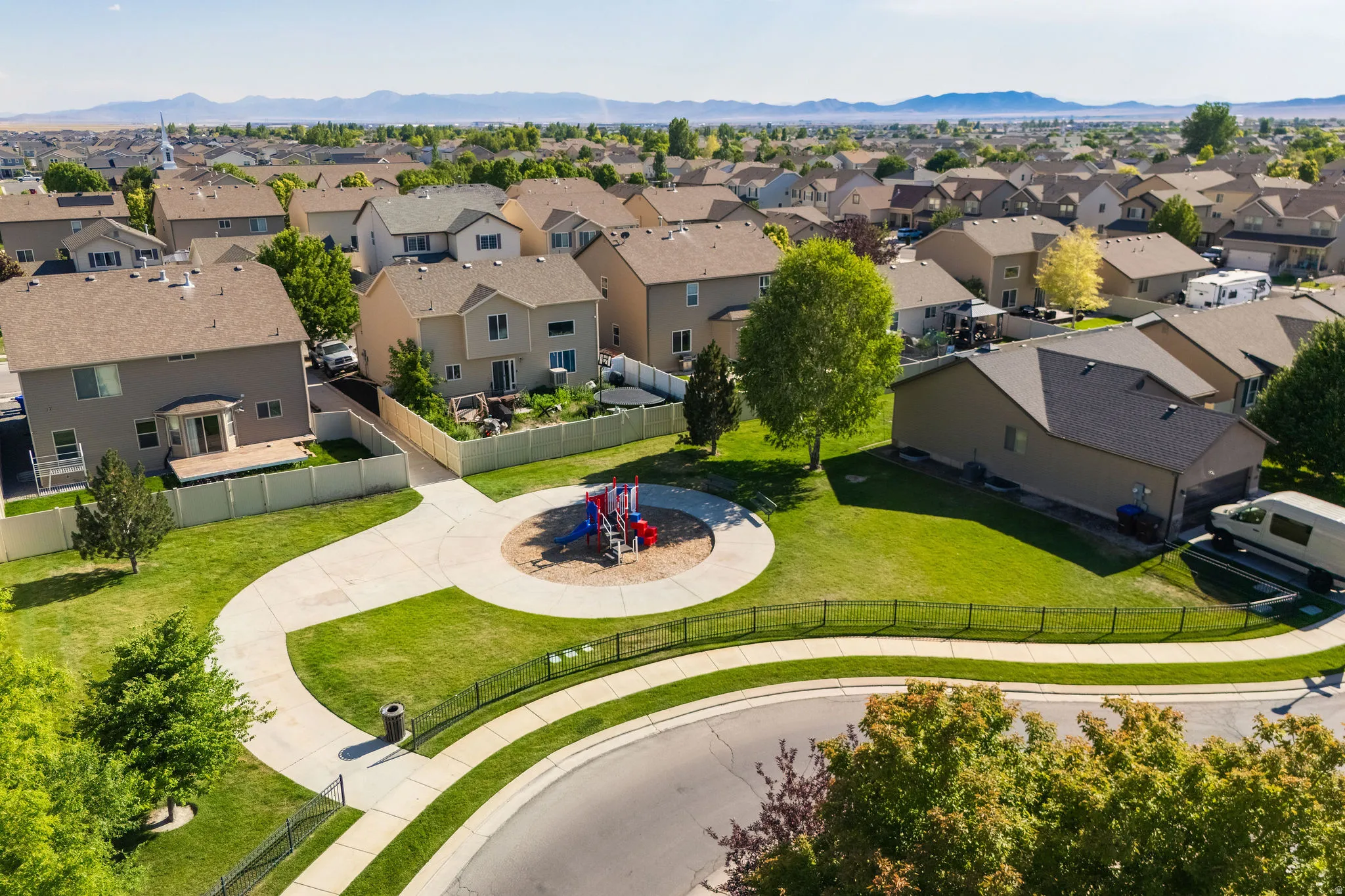 Community green space featuring a circular playground and paved walking paths