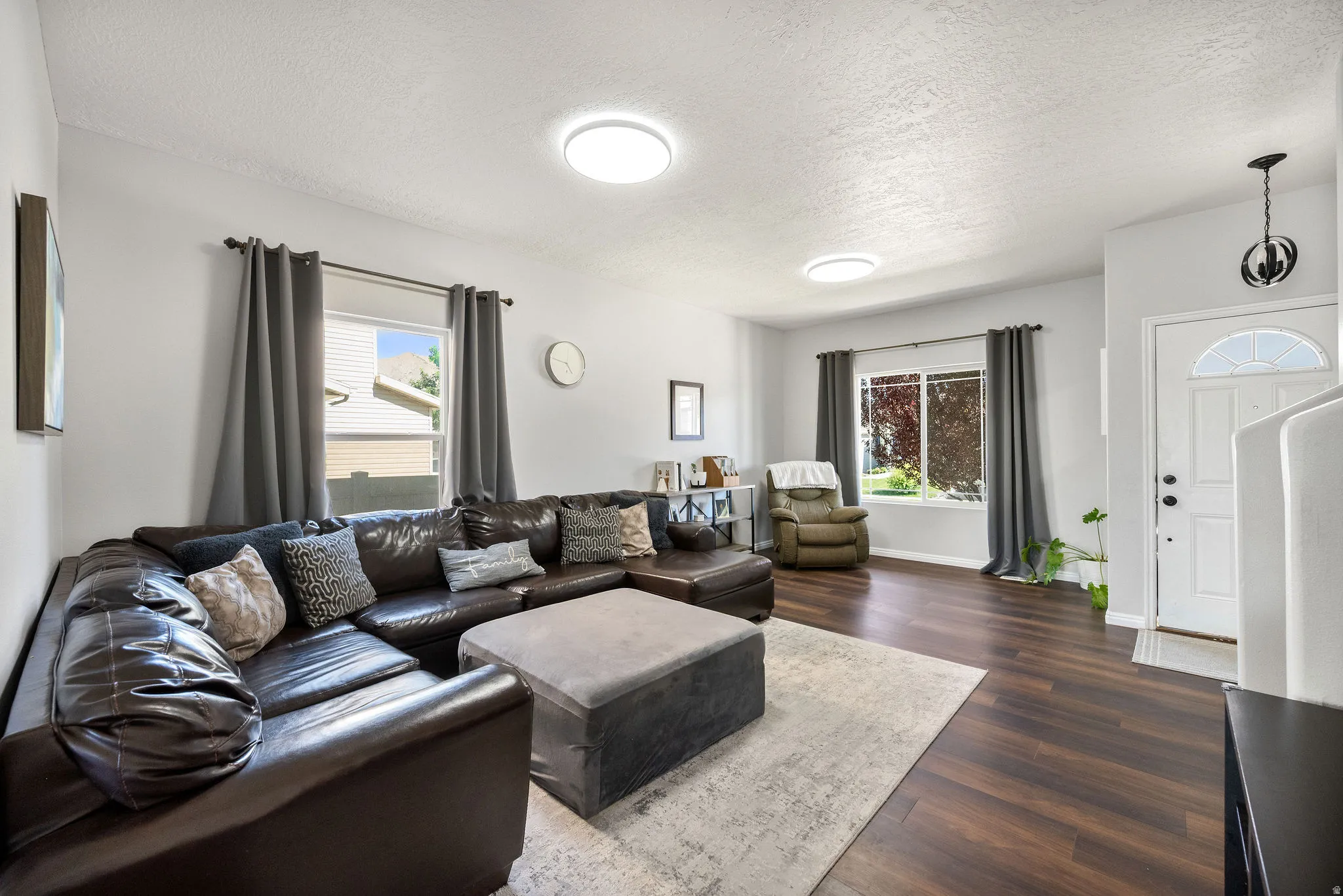 Open living area featuring wood-finish flooring, light grey wall paint, and recessed ceiling lighting