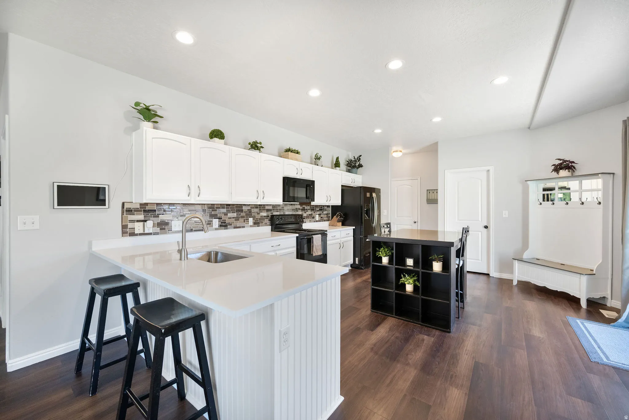 Modern kitchen featuring white cabinetry, light-toned countertops, a mosaic tile backsplash, dark wood-finish flooring, and recessed lighting