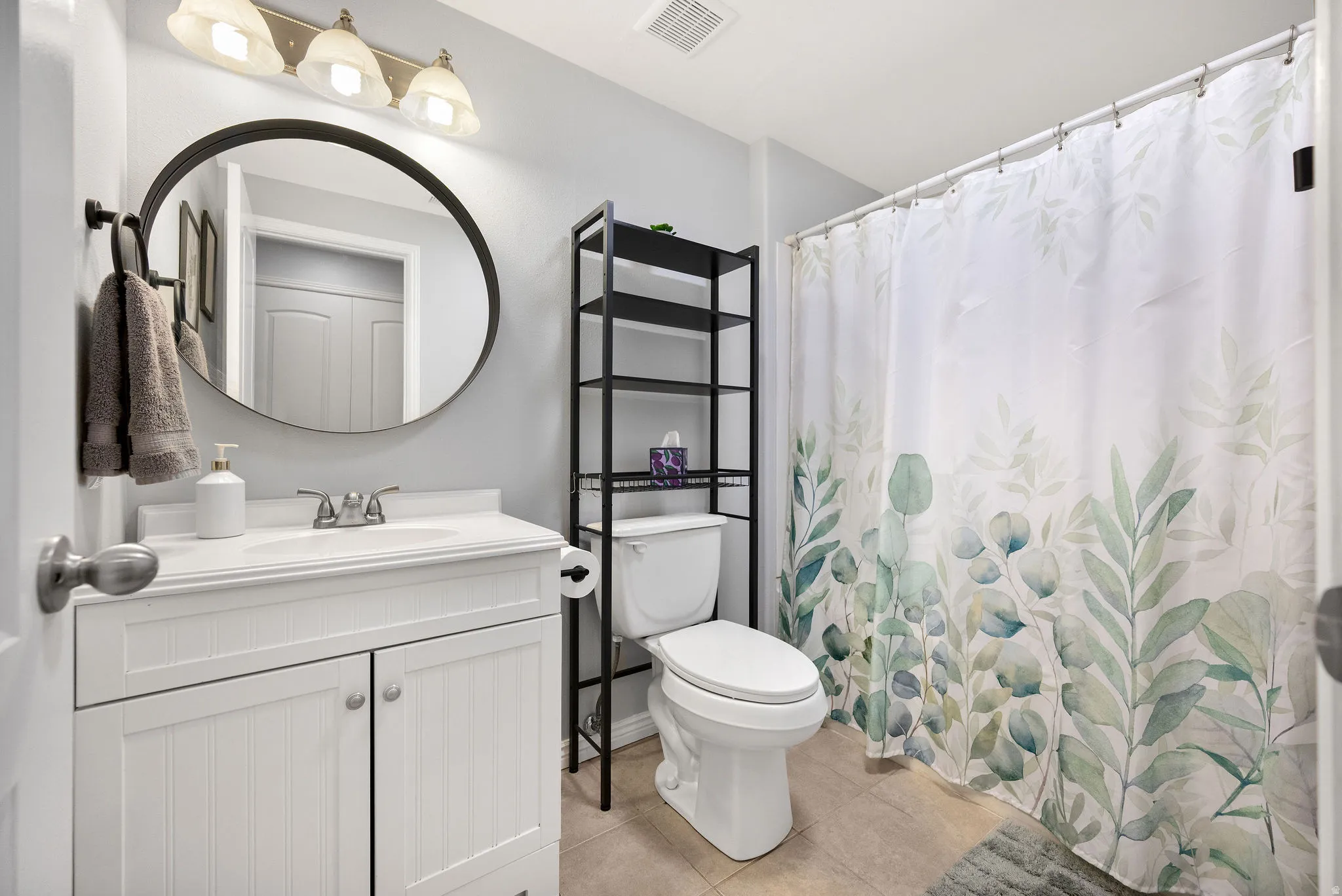 Bathroom featuring a white vanity with integrated sink, brushed nickel faucet, and a large round mirror