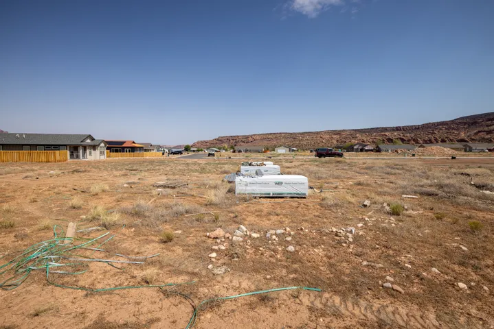 Expansive undeveloped land parcel featuring a rugged natural landscape and distant red rock formations