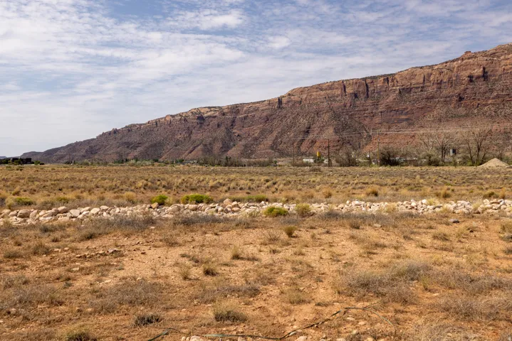 Expansive desert landscape featuring a prominent red rock mountain backdrop