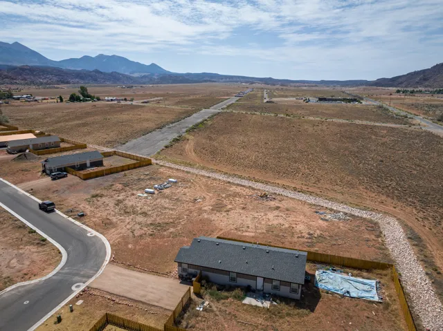 Expansive desert landscape with distant mountain ranges and scattered residential properties