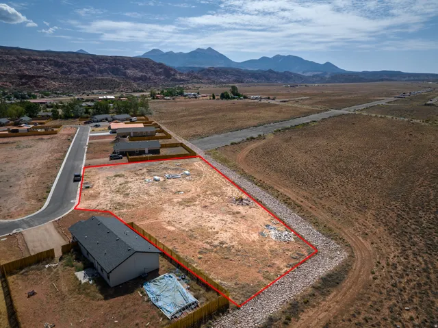 Expansive undeveloped land parcel outlined in red, featuring a partial paved road frontage and surrounding natural terrain