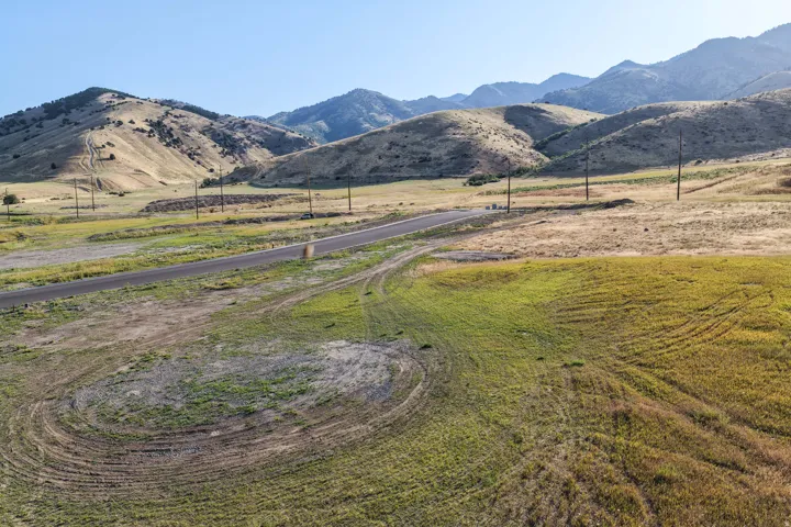 Expansive undeveloped land featuring a paved road, natural terrain, and prominent mountain backdrop