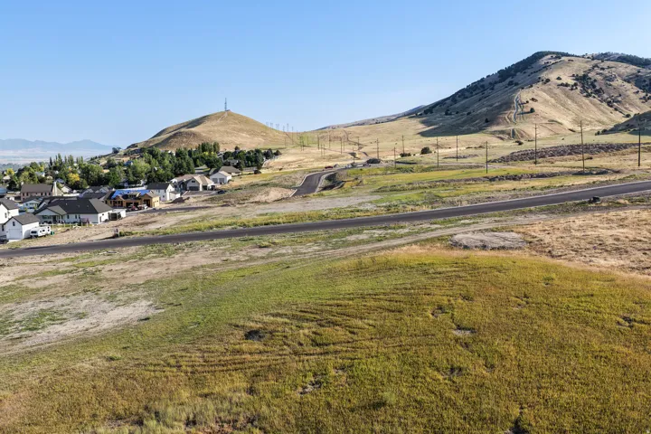 Expansive undeveloped terrain featuring a paved road and established residential structures in the distance
