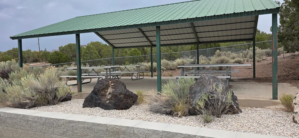 Covered outdoor pavilion with a green corrugated metal roof and exposed metal framing at Old Iron Town Historic Site