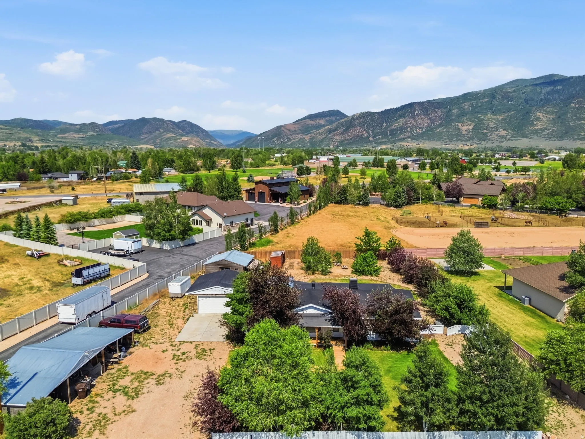 Ranch-style residence featuring a prominent front porch, an attached garage, and mature landscaping