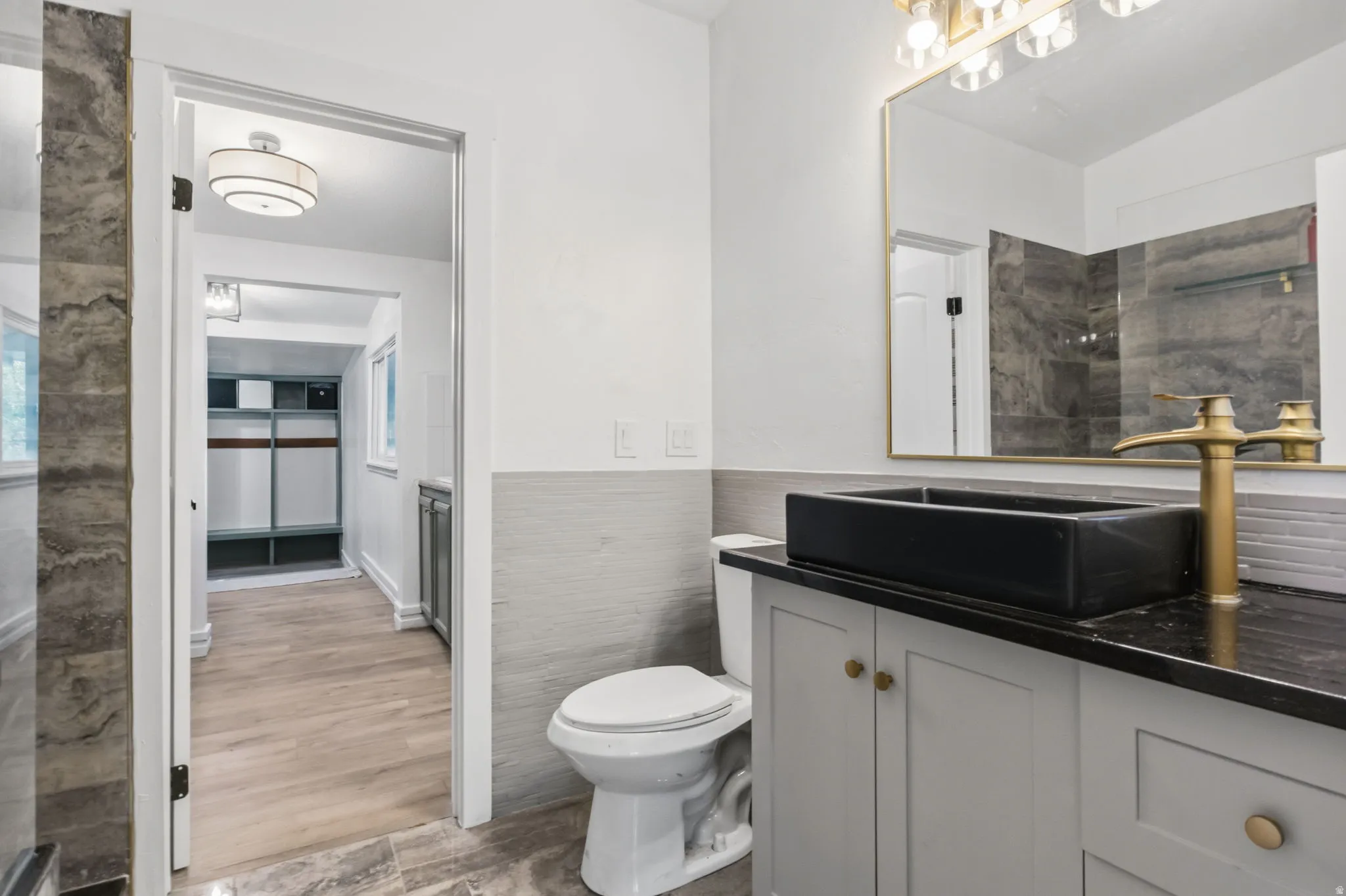 Bathroom featuring a vessel sink, gold-finish faucet, and coordinating vanity with gold-tone hardware