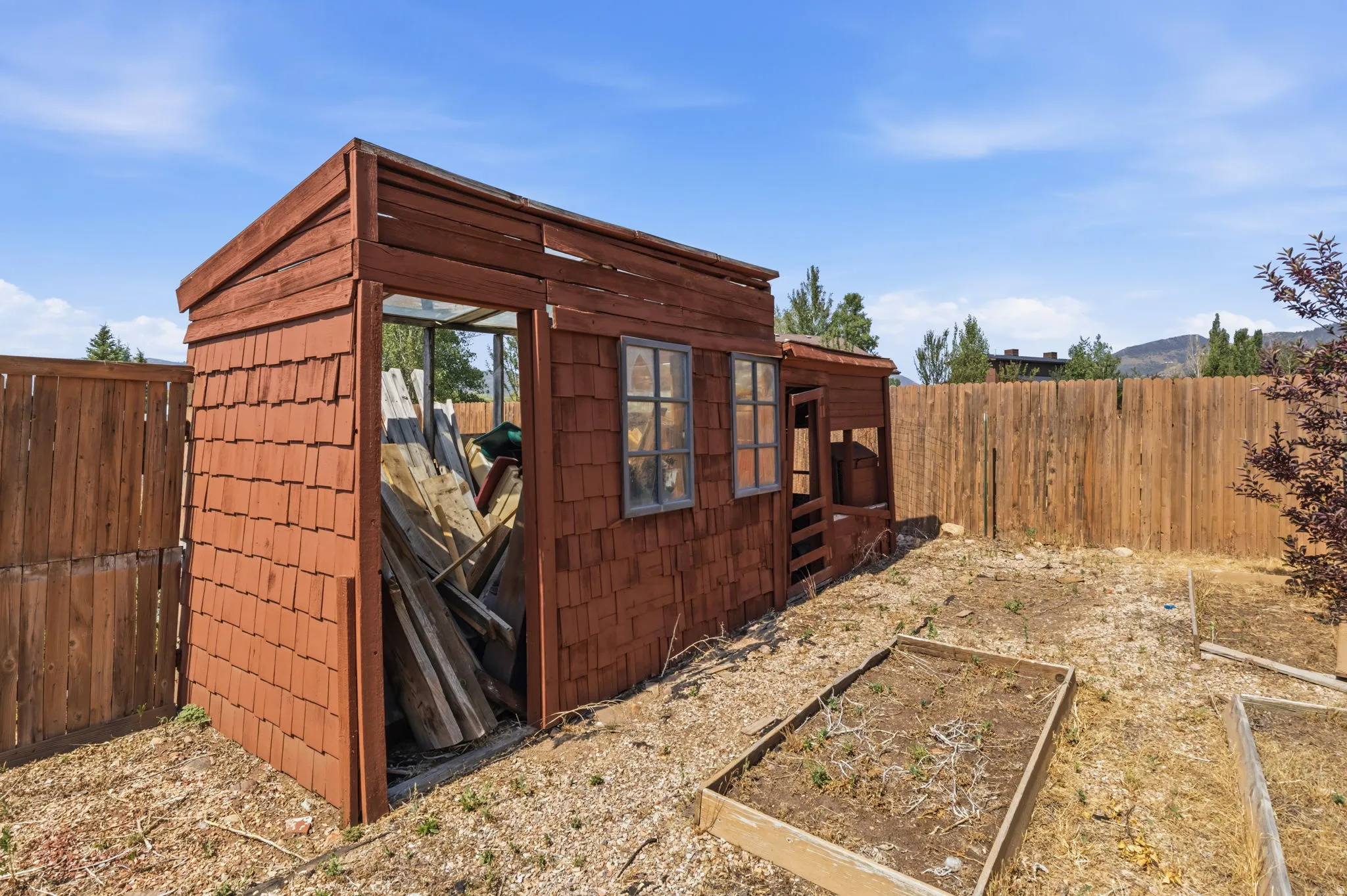 Wood-paneled outbuilding featuring multiple windows and an open doorway