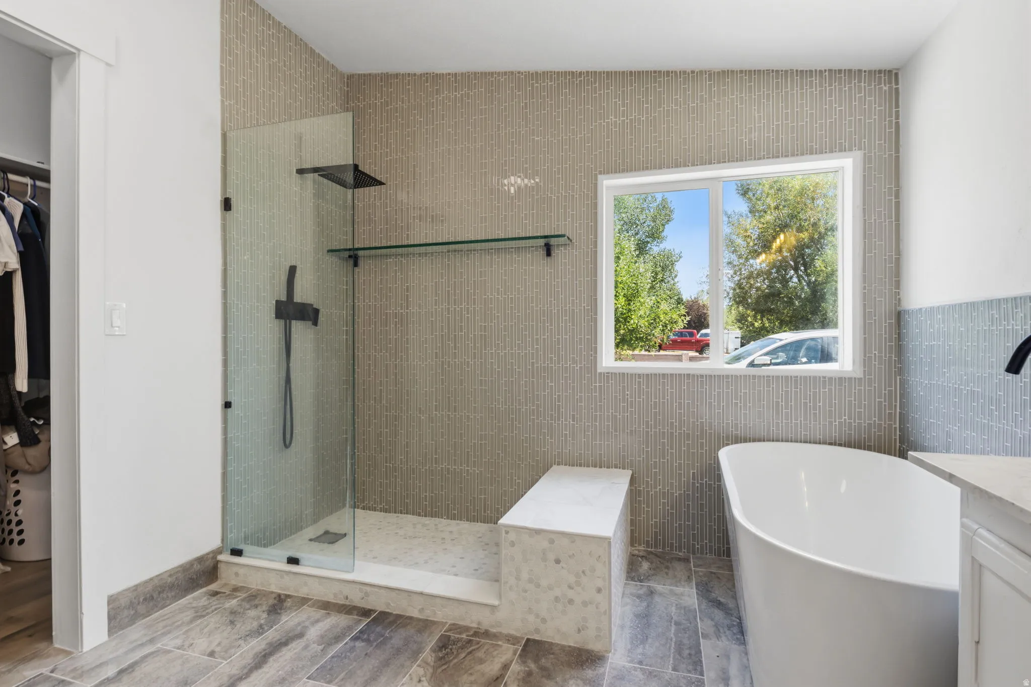 Modern bathroom featuring a freestanding soaking tub, a frameless glass shower enclosure with matte black fixtures, a built-in shower bench, and floor-to-ceiling tilework
