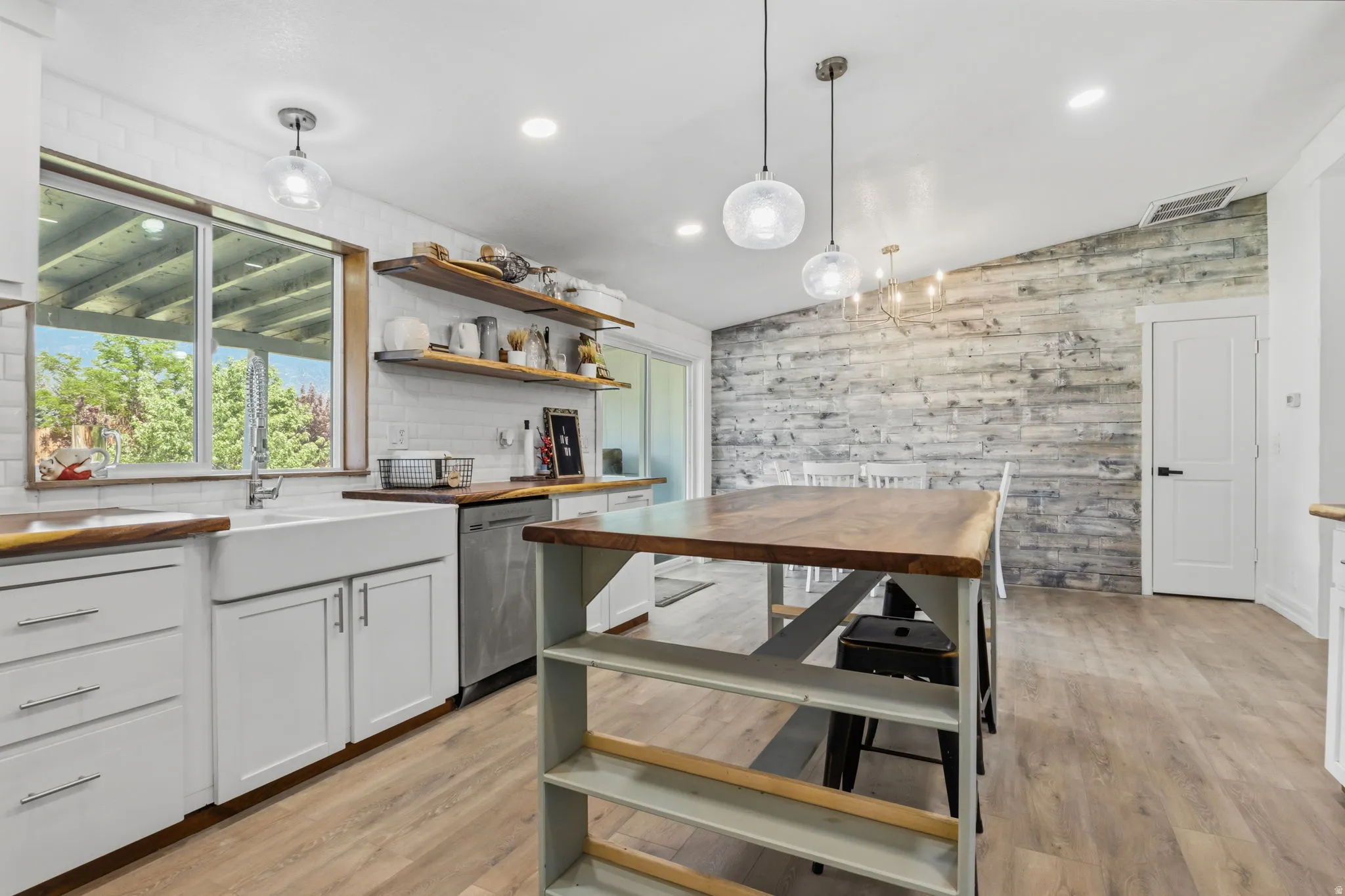 Kitchen featuring light wood-finish flooring, white cabinetry with silver hardware, and a white farmhouse sink