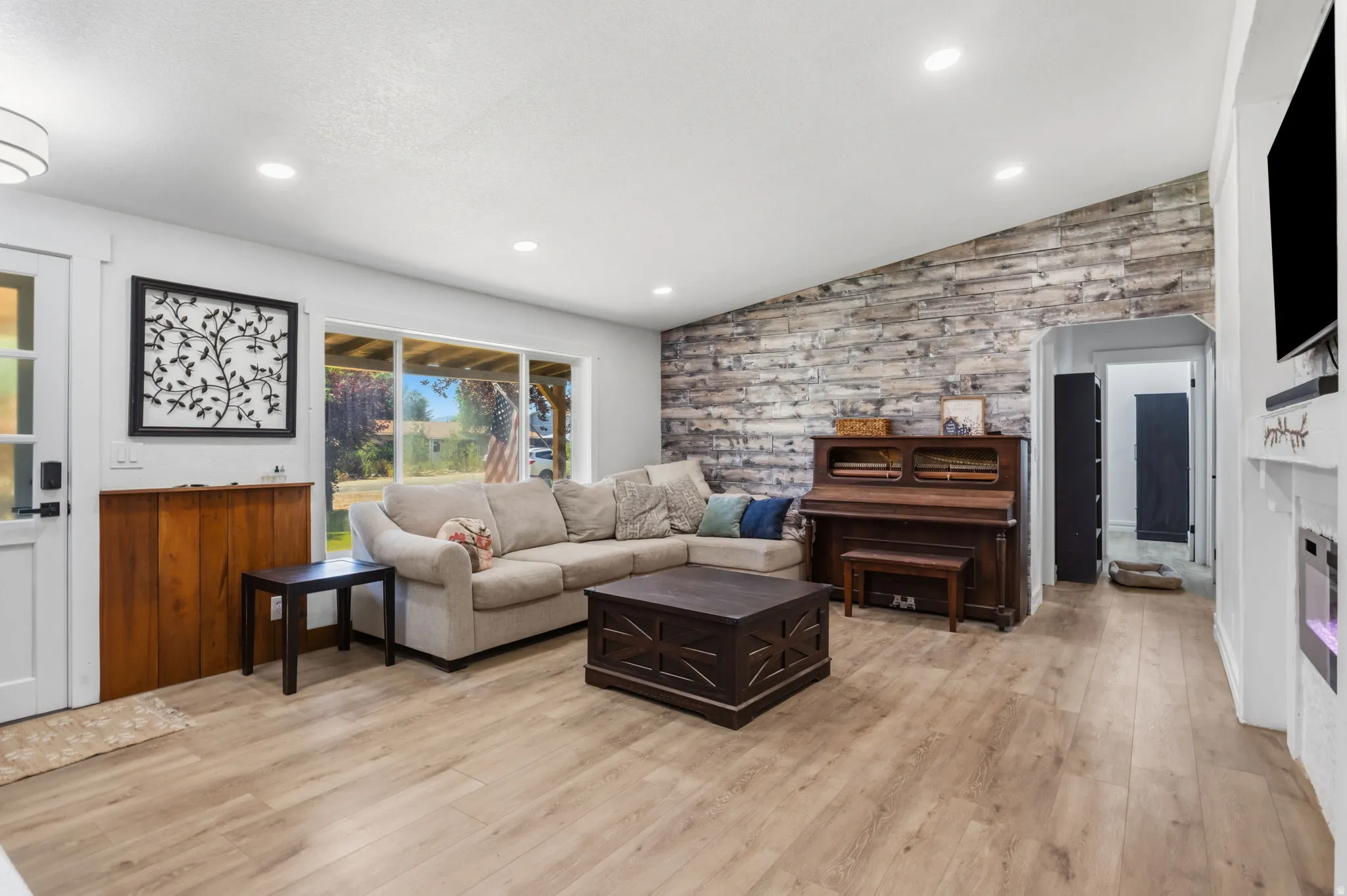 Spacious living area featuring wood-finish flooring, a textured accent wall, and recessed lighting