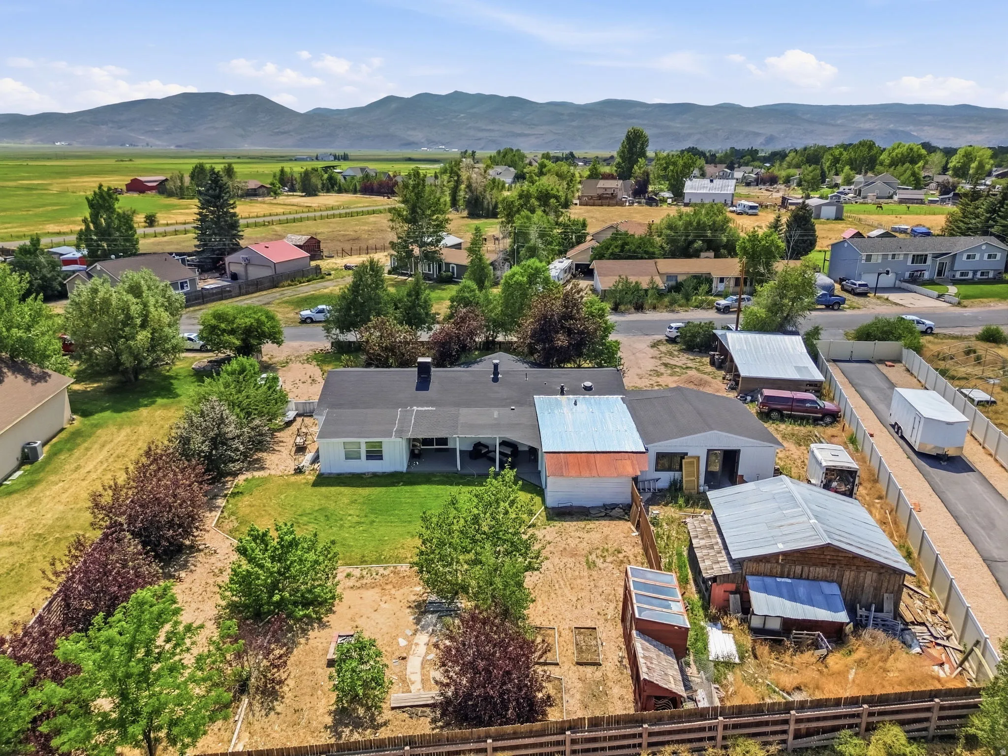 Expansive property featuring a single-story residence with a covered patio, multiple outbuildings, and mature landscaping