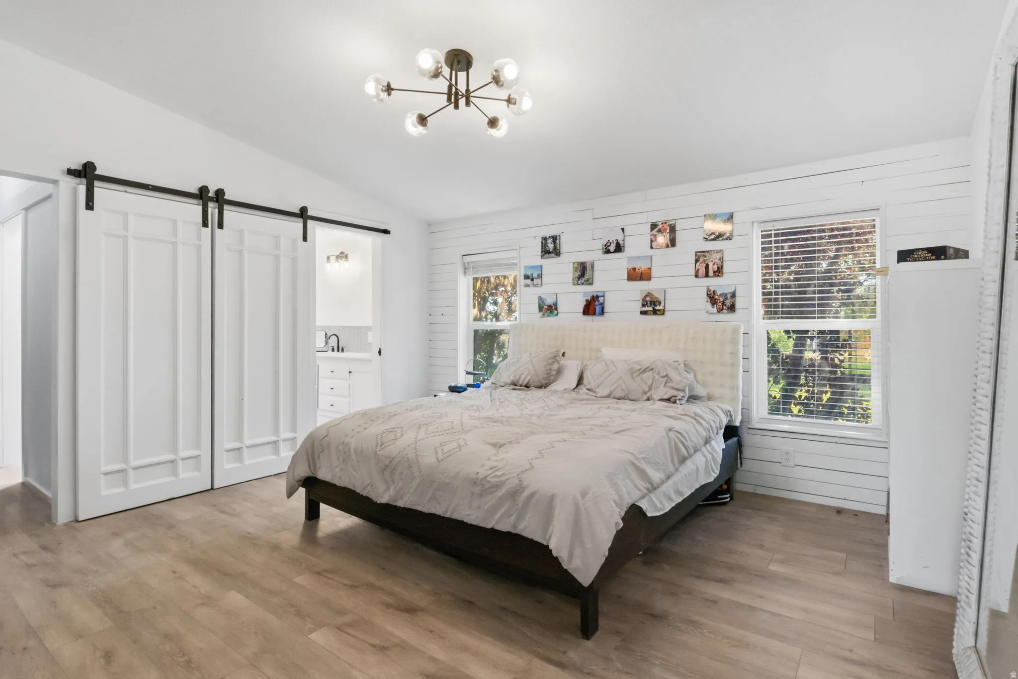 Spacious room featuring wood-finish flooring, a modern sputnik chandelier, and a white shiplap accent wall