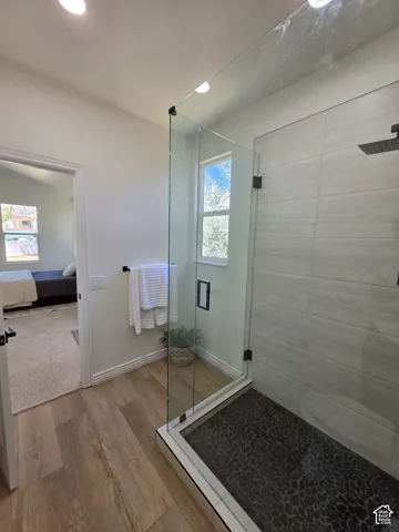 Glass-enclosed shower with textured dark tile flooring and light-toned wall tile