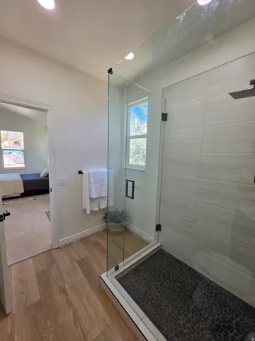 Glass-enclosed shower with textured dark tile flooring and light-toned wall tile