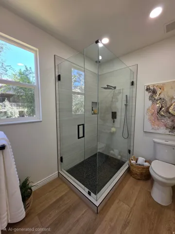 Spacious glass-enclosed shower with pebble-finish flooring and tile surround