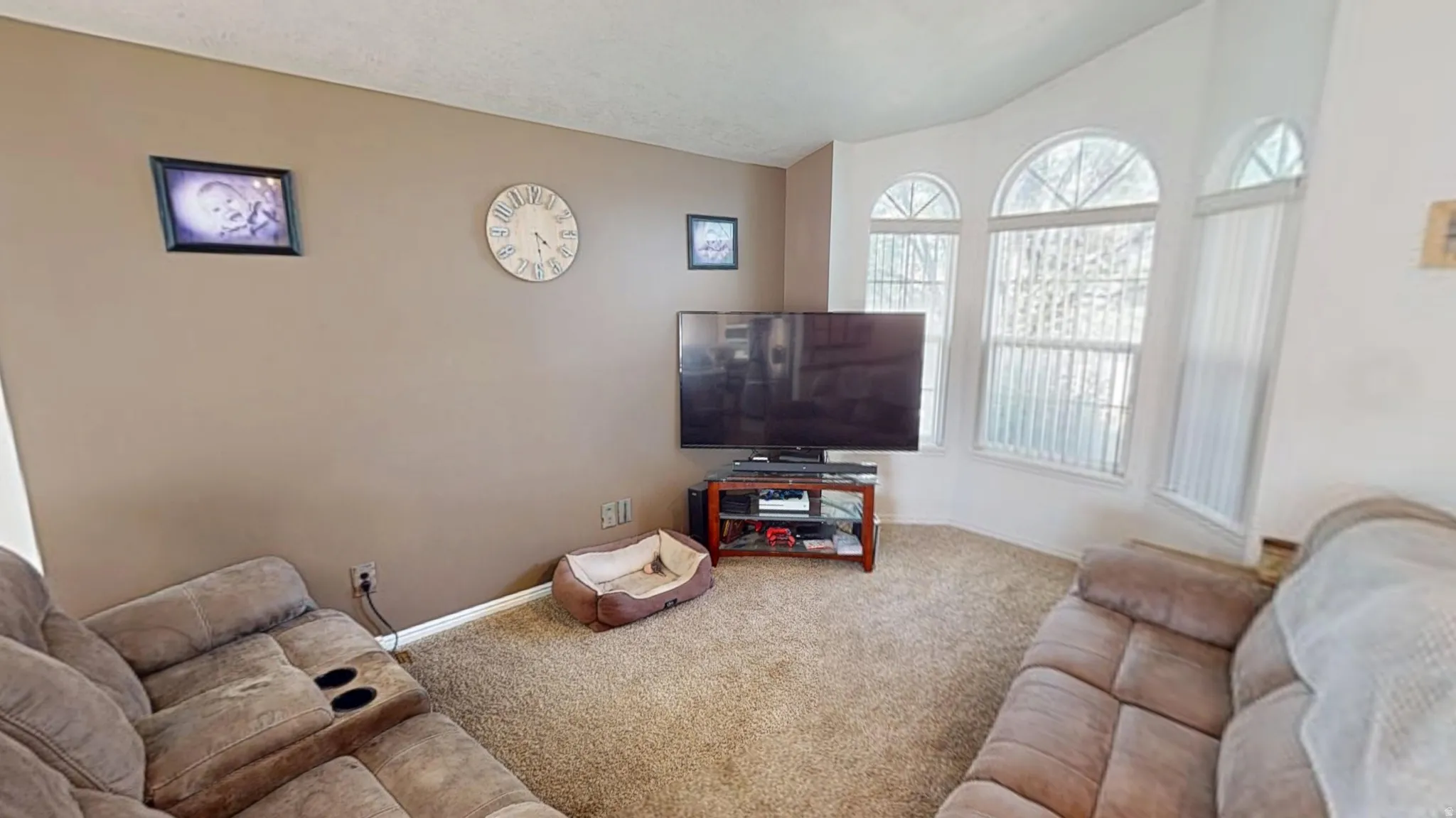 Bay window with arched upper panes and vertical blinds, complemented by neutral wall tones and textured carpeting