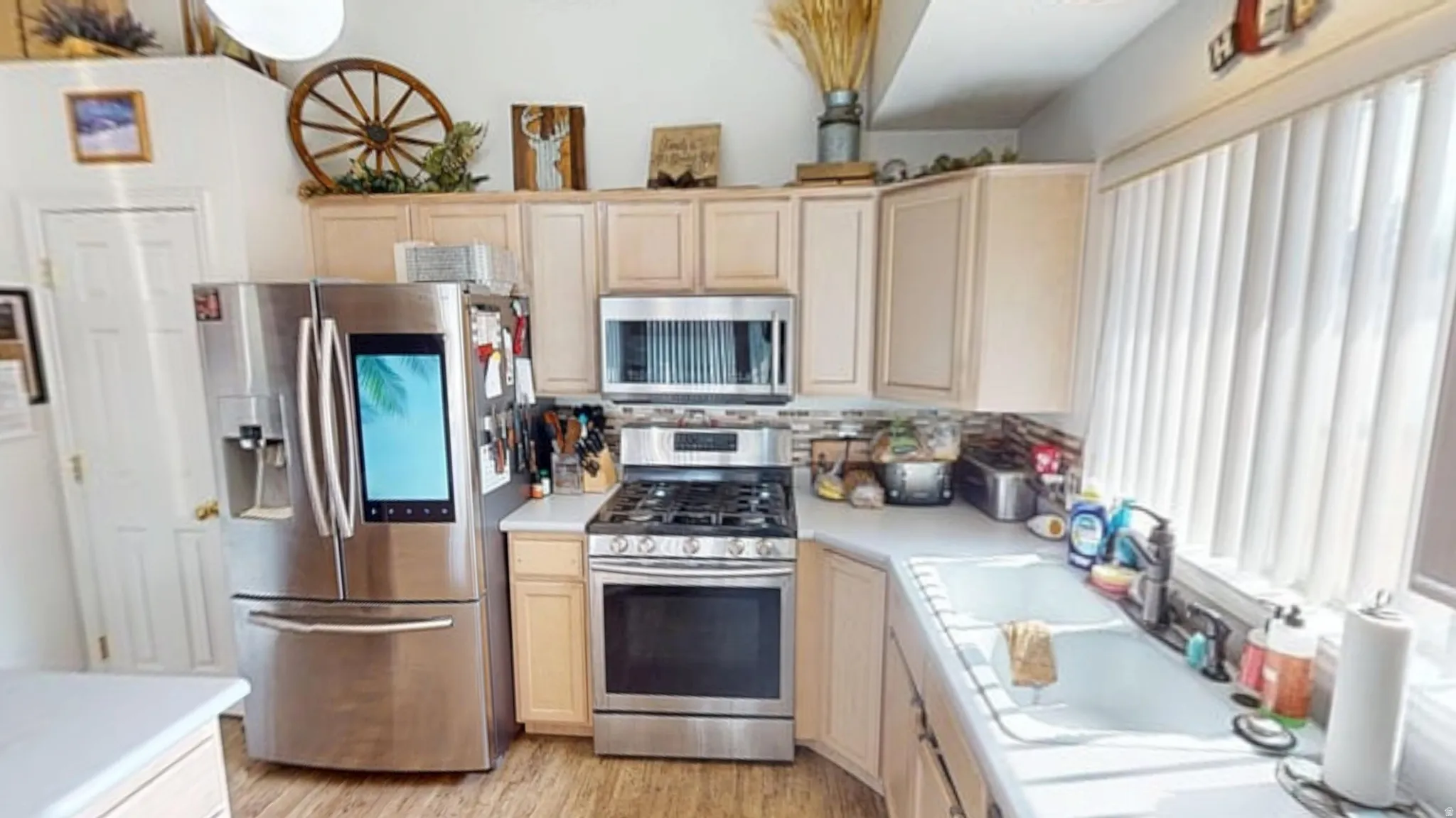 Kitchen featuring light wood cabinetry, stainless steel appliances, and a tile backsplash