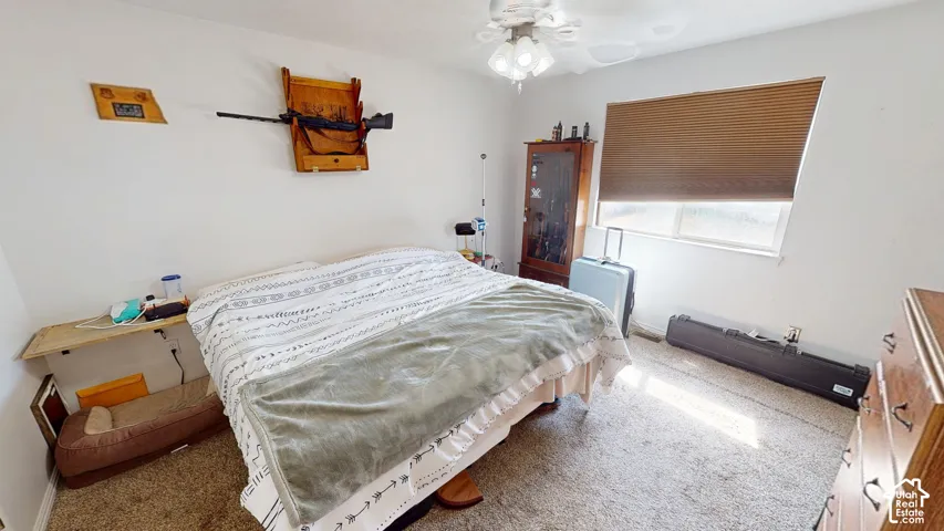 Carpeted room featuring a ceiling fan, a window with blinds, and white walls