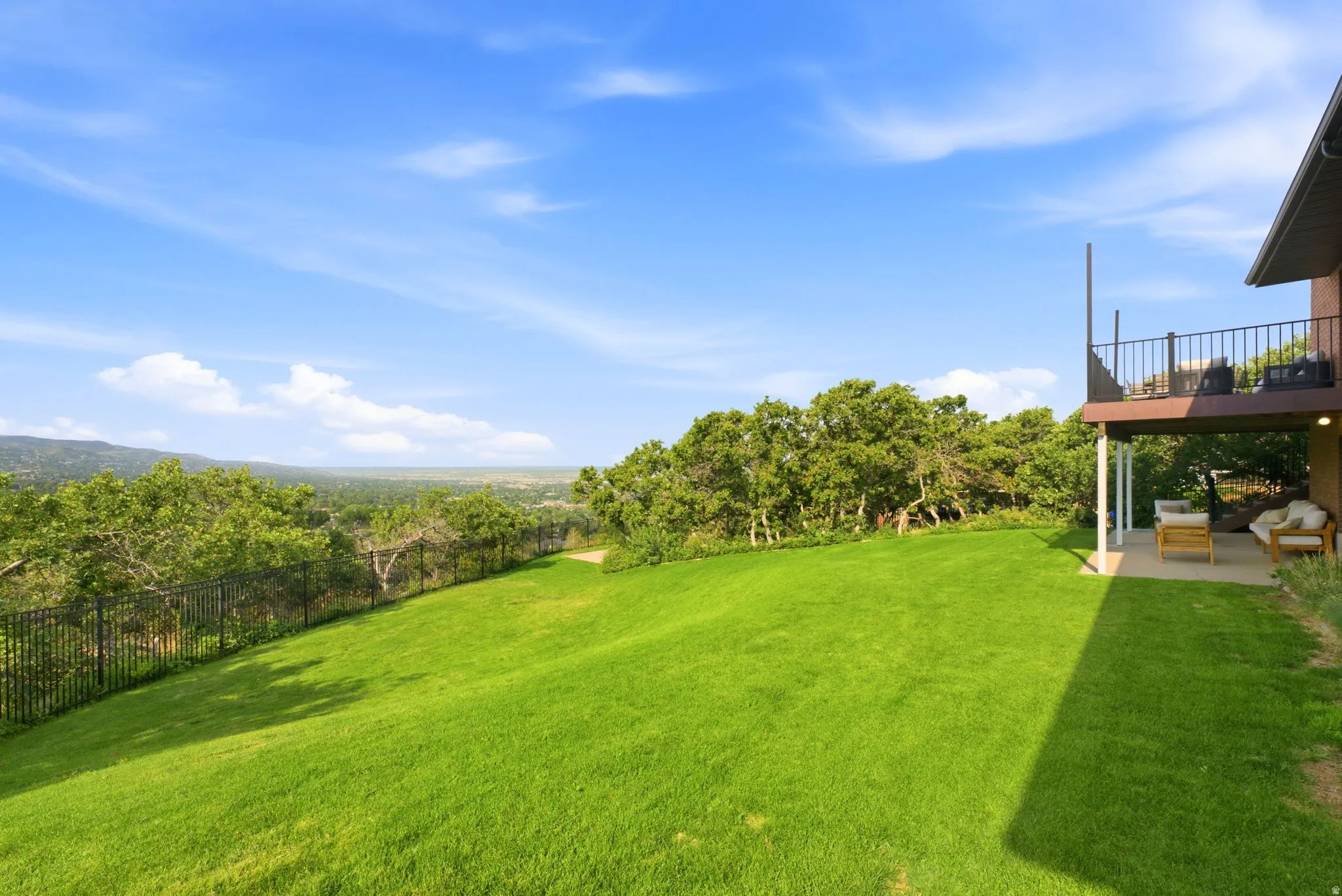 Expansive green lawn sloping towards a distant tree line and horizon