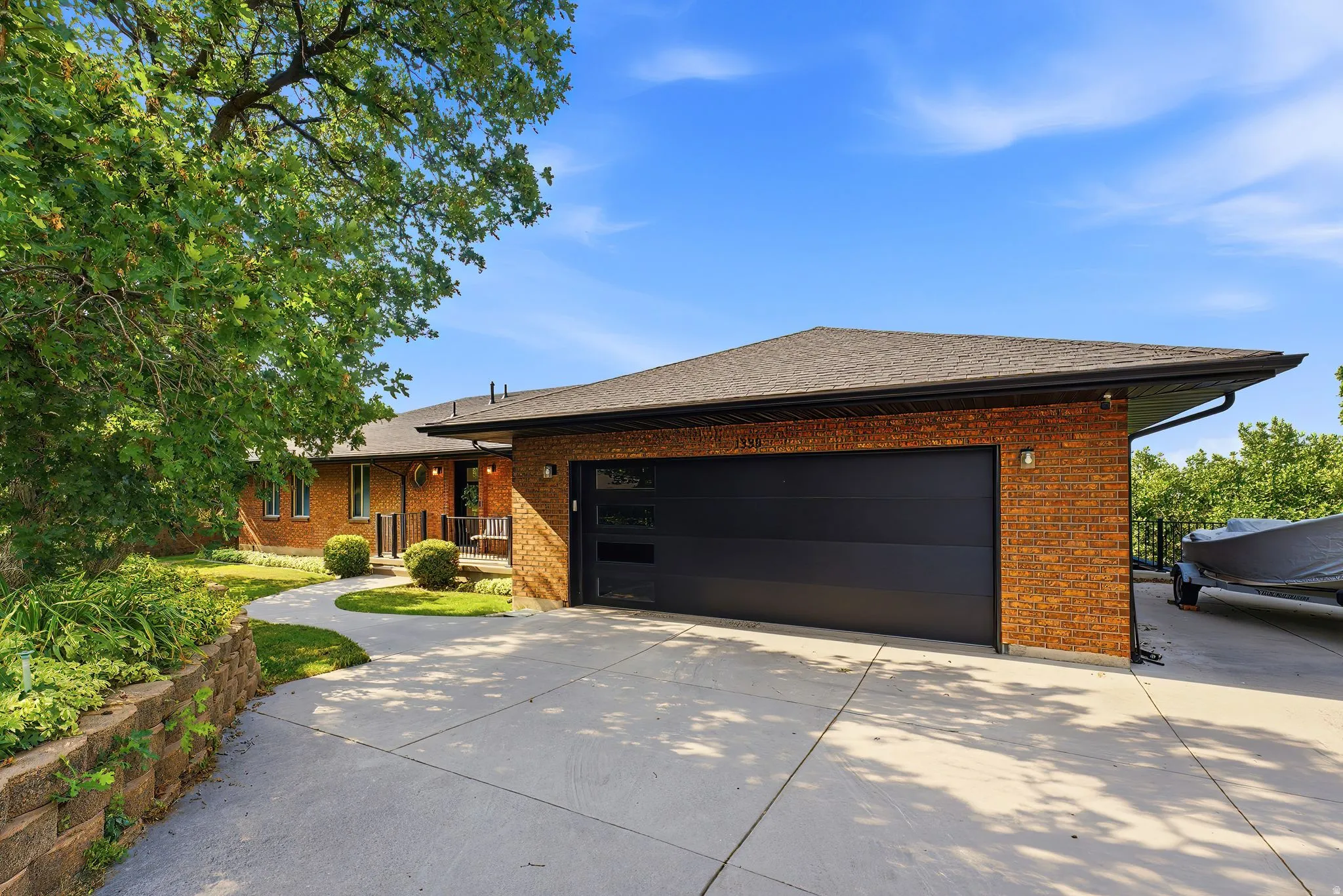 Brick exterior featuring a black garage door with frosted window panels, a concrete driveway, and a paved walkway leading to the front entry