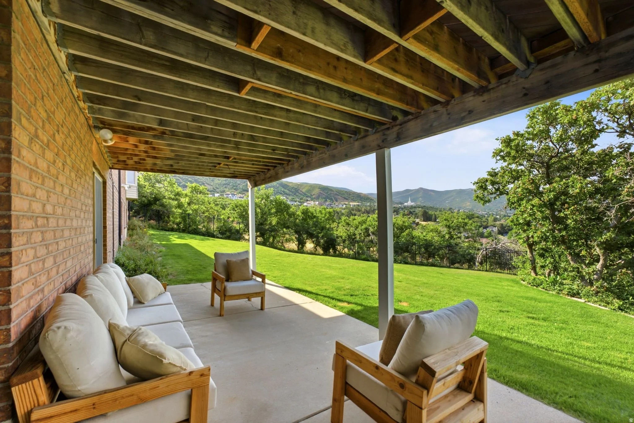 Covered patio featuring an exposed wood beam ceiling, concrete flooring, and a brick exterior wall