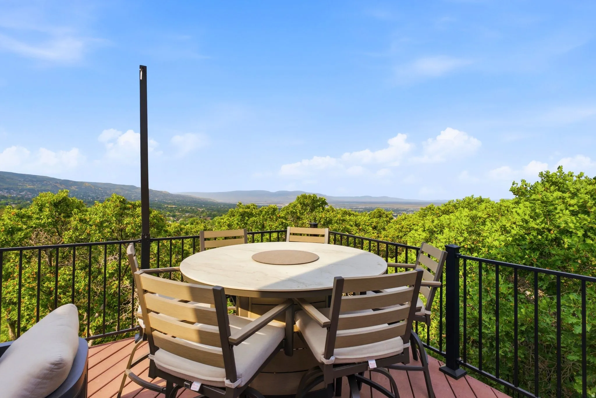 Expansive outdoor deck with composite decking, black metal railing, and panoramic mountain scenery