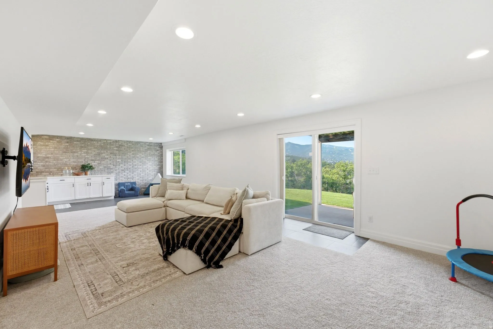Spacious entertainment area featuring recessed lighting, a sliding glass door, and mountain scenery