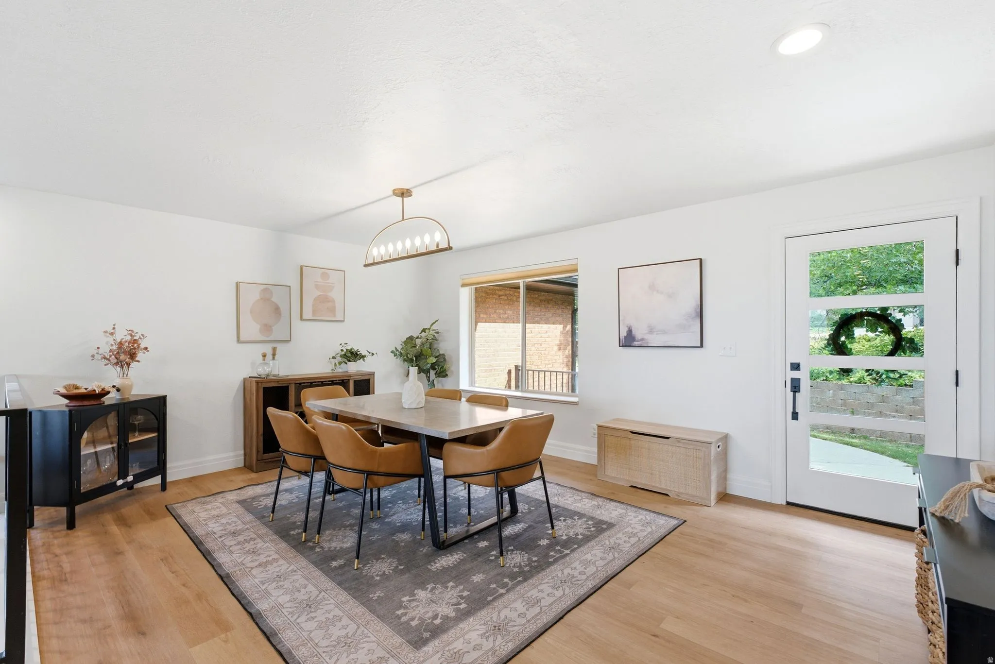 Bright dining area with wood-finish flooring, a modern linear chandelier, and a large window