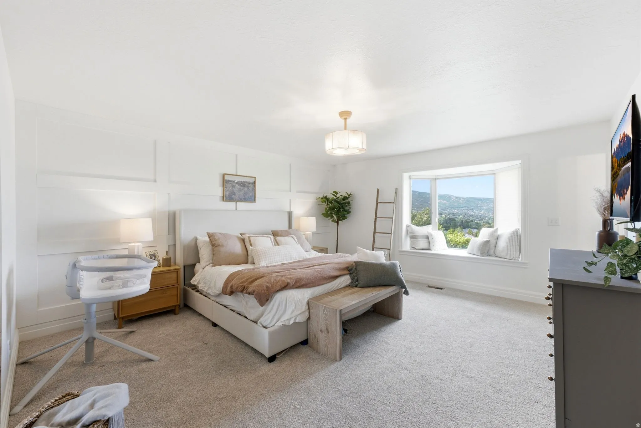 Spacious room featuring a large bay window, wall paneling, and a light-colored carpet