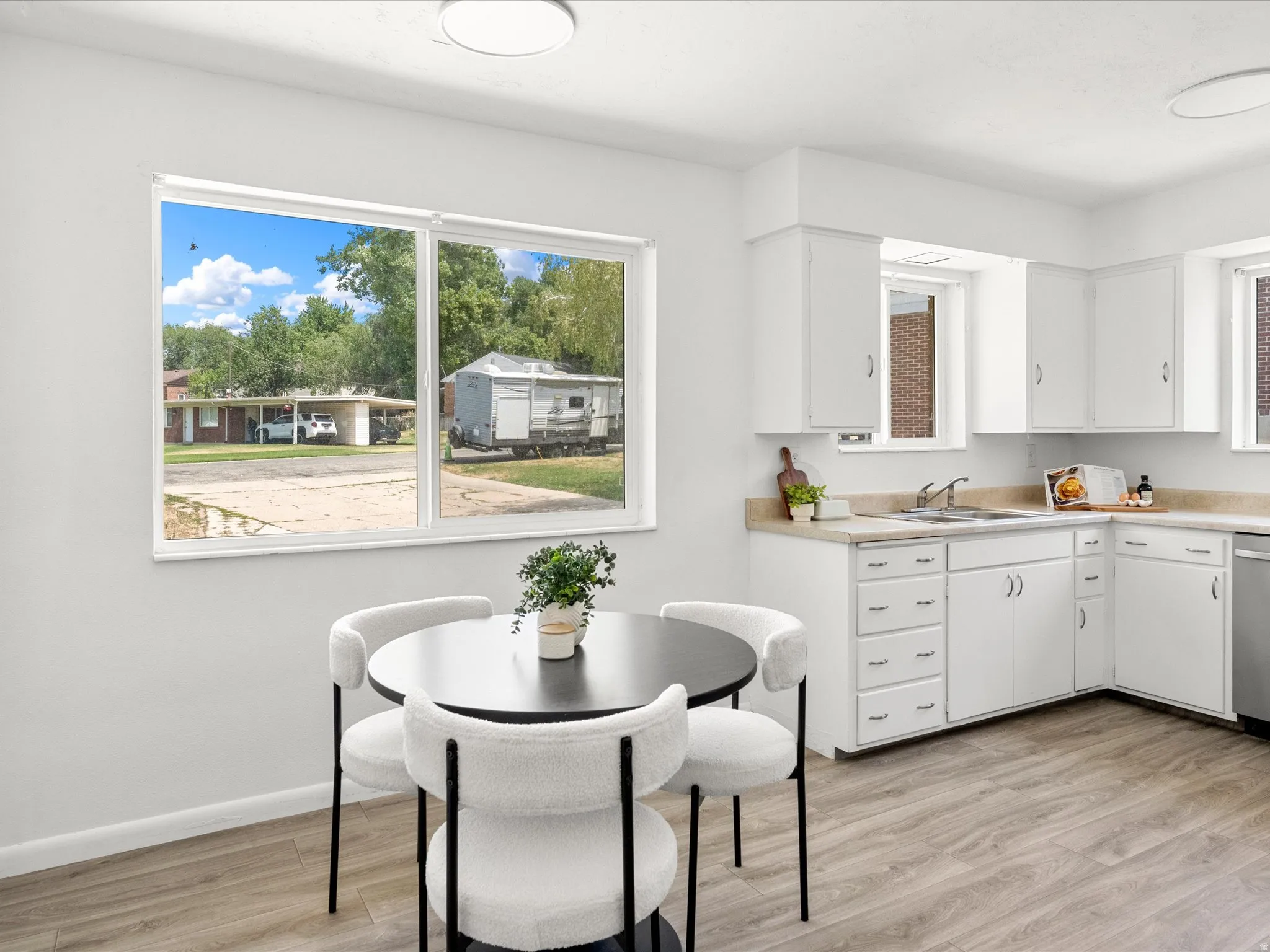 Bright kitchen with light wood-finish flooring, white cabinetry, and light countertops