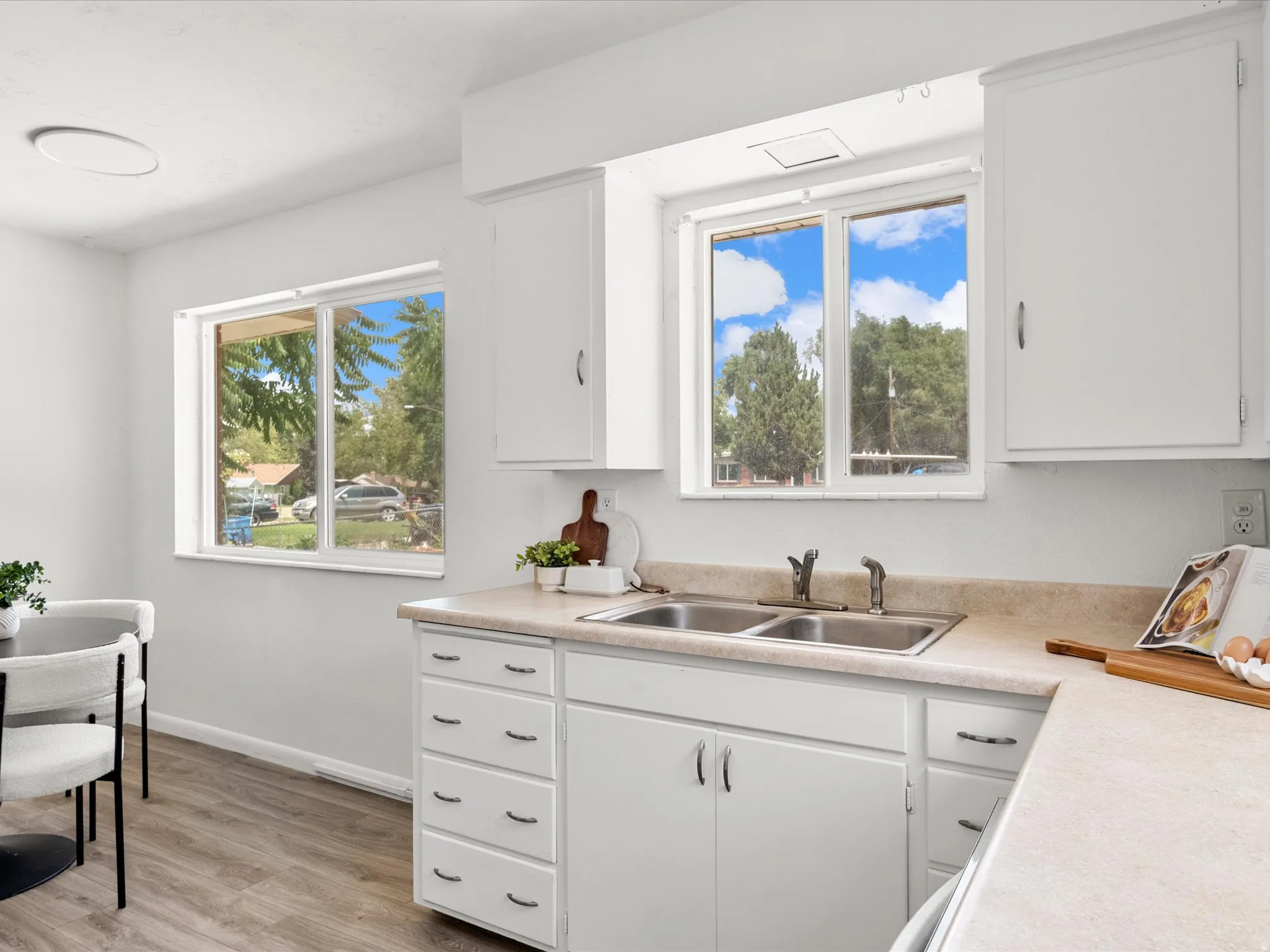 Kitchen featuring white cabinetry, light-toned countertops, and a double basin sink with a chrome faucet
