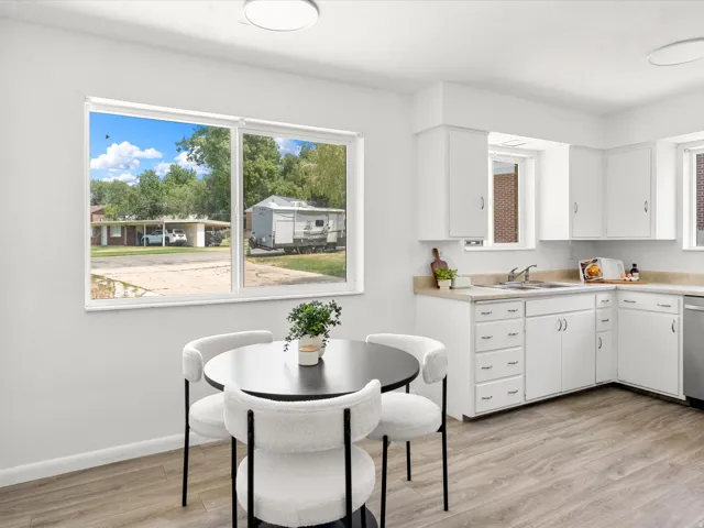 Bright kitchen with light wood-finish flooring, white cabinetry, and light countertops