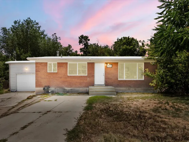 Brick facade residential structure featuring a white entry door, multiple windows, and an attached garage with a white door