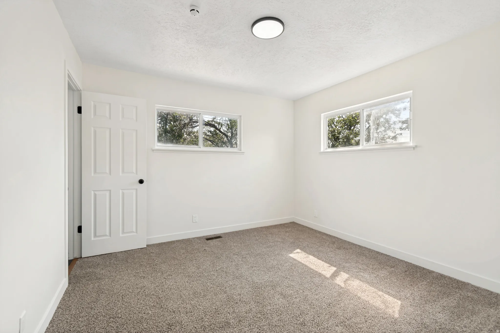 Room featuring light-colored walls and grey carpet flooring