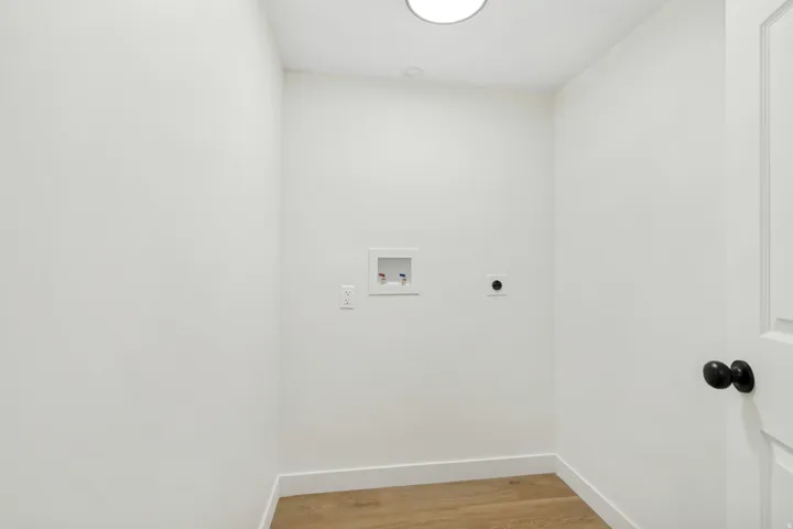 Dedicated utility space featuring light wood-finish flooring, white walls, and a round overhead light fixture